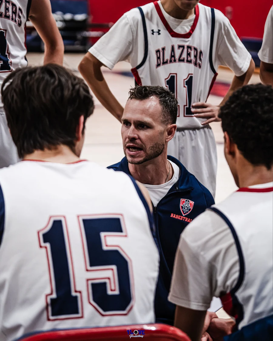 Coach Daniel Pinedo talking with basketball players in a team huddle